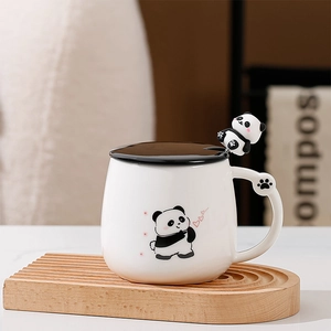 Dettaglio di tazza in ceramica panda con coperchio e cucchiaio su base in legno ondulato