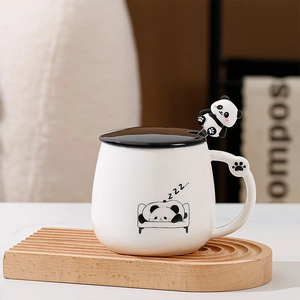 Dettaglio tazza in ceramica panda con coperchio e cucchiaio panda su vassoio in legno