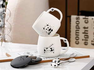 Dettaglio di tazze in ceramica panda con manico a zampa e cucchiai decorativi panda