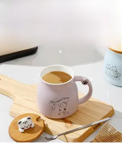 Detail of lavender ceramic cat mug with 3D kitty lid and stainless steel spoon on wooden tray