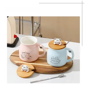 Detailed view of ceramic cat mug with wooden lid featuring a 3D kitten topper and metal spoon