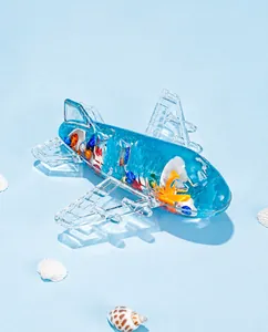 Detalle de pisapapeles de avión con fluido azul estilo océano y pequeñas conchas