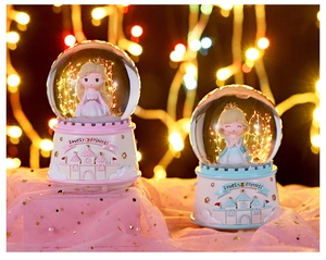 Detail view of pink and blue princess crystal music boxes with LED lights and resin base