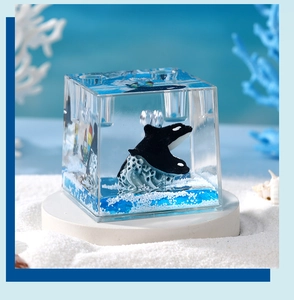 Detailed view of an orca figure inside a transparent resin cube with blue ocean textures