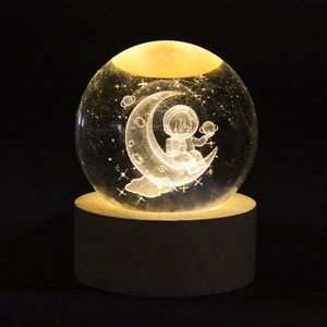 Macro detail of 3D galaxy crystal ball night light with astronaut on a wooden base