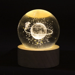 Detail of 3D laser engraved Saturn crystal ball on a glowing wooden base as warm night light