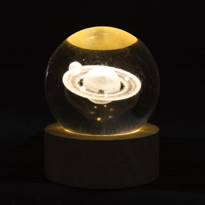 Close-up of 3D laser-engraved Saturn crystal ball with warm light wooden base