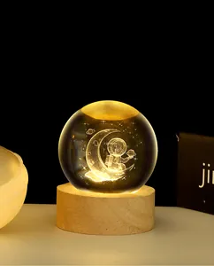 Close-up of 3D crystal ball night light with astronaut moon carving and wooden base