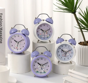 Detail of cartoon twin bell alarm clocks with cute animal dials on a white pedestal