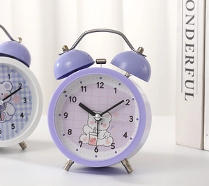 Macro view of mechanical twin bell alarm clock featuring cartoon bear and purple dial