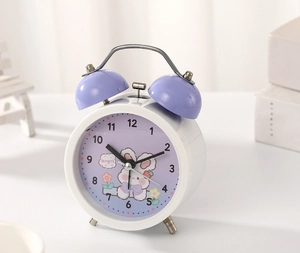 Close-up of a white and purple cartoon rabbit twin bell alarm clock on a desk