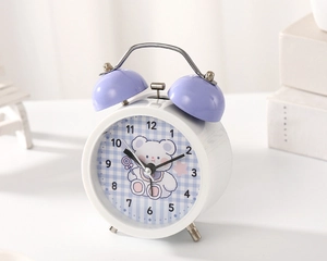 Close-up of white cartoon alarm clock with purple twin bells and cute bear pattern