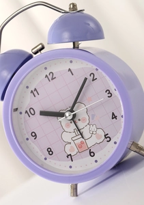 Detail of purple twin bell alarm clock featuring a cute cartoon bear and analog dial
