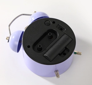 Detailed back view of purple mechanical alarm clock with adjustment knobs and battery compartment