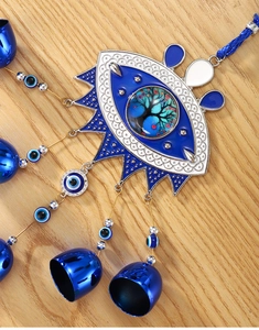 Detail of Tree of Life evil eye wall hanging with blue metal bells on wooden background