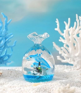 Detailed close-up of a glass candy-shaped ocean ornament with dolphins and coral inside