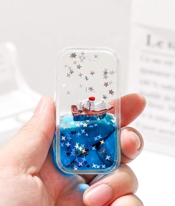 Détail de l'acrylique rectangulaire à sable liquide avec bateau et paillettes bleues