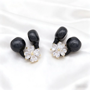 Detail of flower ear clips with black spheres and heart-shaped crystals on white silk