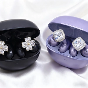 Detail of TWS earphones with luxury crystal flower and clover jewelry buckle on silk