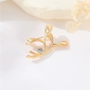 Elegant gold ginkgo leaf brooch with a brilliant zircon accent on a minimalist background
