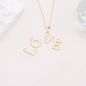 Detailed macro view of 14k gold plated alphabet LOVE charms with white enamel inlay