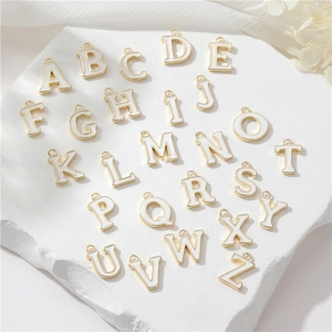 Macro shot of 26 gold and white enamel letter charms for personalized jewelry making