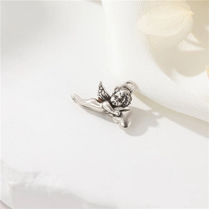 Close-up of vintage silver Cupid angel charm with heart and detailed wing texture