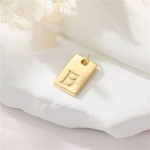 Elegante 14K vergulde rechthoekige hanger met reliëfletter B op een wit stenen ondergrond