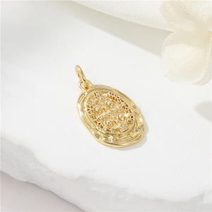 Macro detail of a 14K gold-plated oval Saint Benedict medal pendant on white stone