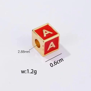 Macro view of 0.6cm gold-plated cube alphabet bead with red enamel and letter A