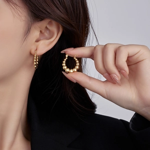 Orecchini a cerchio dorati con sfere metalliche graduate mostrati sul modello per look trendy