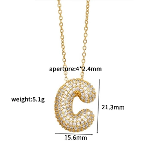 Macro detail of gold C-letter pendant with zircon stones and precise dimensions