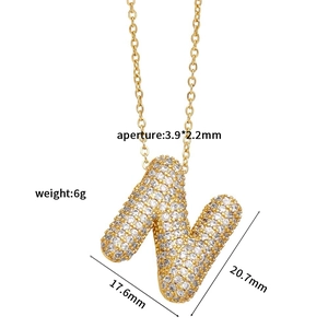 Macro view of gold-plated capital letter N pendant with micro-paved white cubic zirconia
