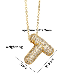 Macro detail of gold-plated letter T pendant with micro-pave cubic zirconia on white base