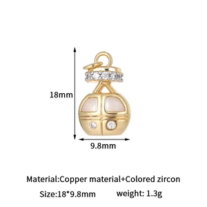 Detailed view of a gold lantern charm made of copper with white shell inlay and zircons