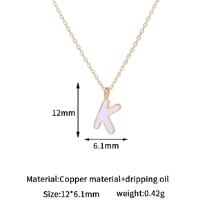 Detalle del colgante letra K de cobre bañado en oro de 14K con acabado de esmalte rosa