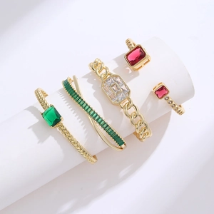Goldene Armreifen und Ringe Set mit Smaragd und Rubin Edelsteinen auf weißem Display