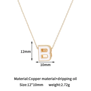 Macro detail of 14K gold plated copper letter B pendant with white enamel oil drip