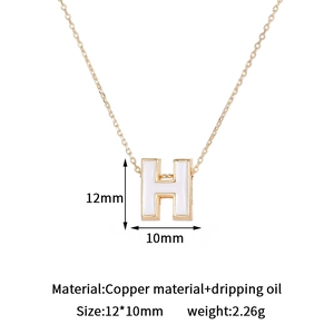 Detailed macro view of gold-plated letter H pendant with white enamel and product dimensions
