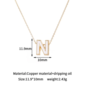Detail of 14K gold plated letter N pendant with white enamel dripping oil inlay