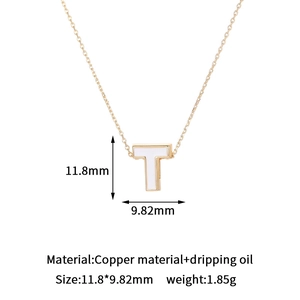 Detailed view of white enamel letter T pendant with 14K gold plating and measurements