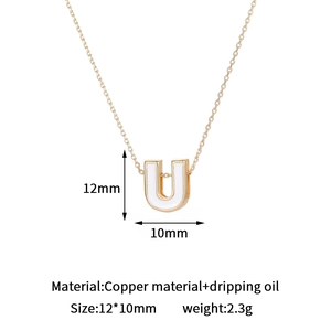 Detail view of gold letter U pendant with white enamel inlay, measuring 12x10mm