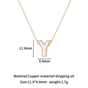 Macro detail of gold-plated letter Y charm with white enamel drip oil and copper base