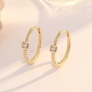 Detail of 14K gold twisted chain hoop earrings with square zircon stone setting