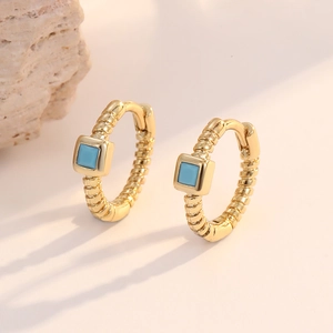 Detail view of 14K gold twist hoop earrings featuring square turquoise gemstone inlays