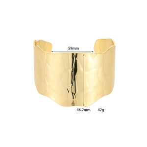 Dettaglio di un ampio bracciale in metallo dorato martellato con larghezza di 46,2 mm