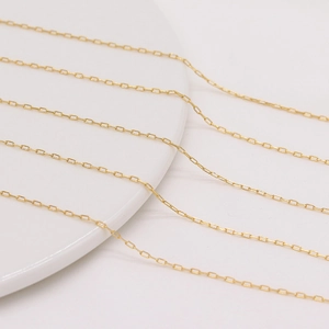 Collana a catena rettangolare dorata lucida esposta su supporto in ceramica bianca