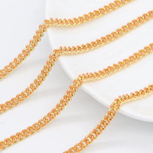 Dettaglio macro della catena dorata con decorativi puntini in smalto arancio-rosa