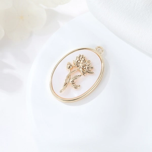 Dettaglio pendente ovale in madreperla con rilievo floreale oro 14K su seta bianca