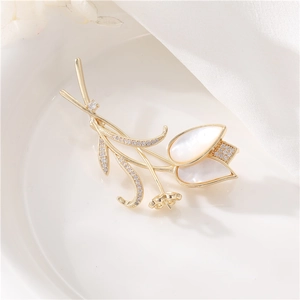 Détail macro de broche tulipe avec base dorée, pétales en nacre et pavage de zircons